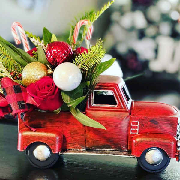Red rose arrangement in a red toy truck with candy cane accents