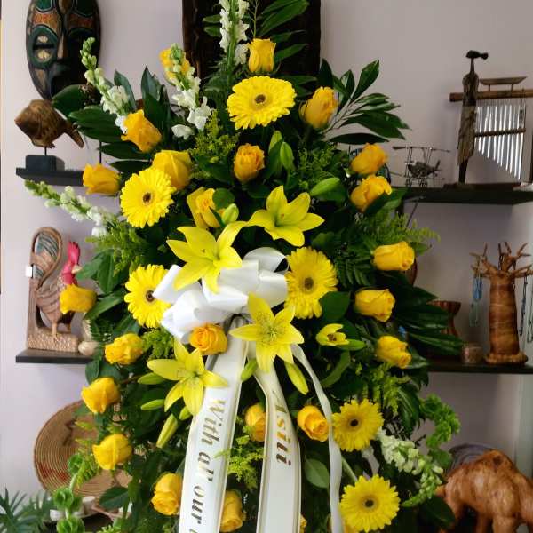 Large yellow floral standing spray with ribbon on an easel