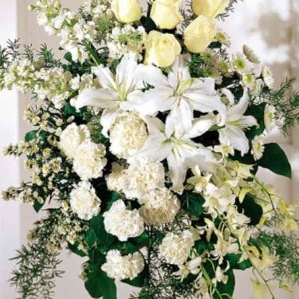 White lilies and pale yellow roses in a standing floral spray