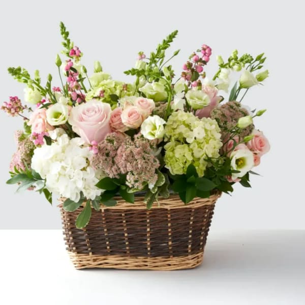 Pink and white mixed flower arrangement in a wicker basket