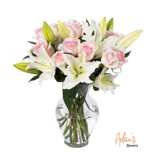 Pink roses and white lilies arranged in a clear glass vase