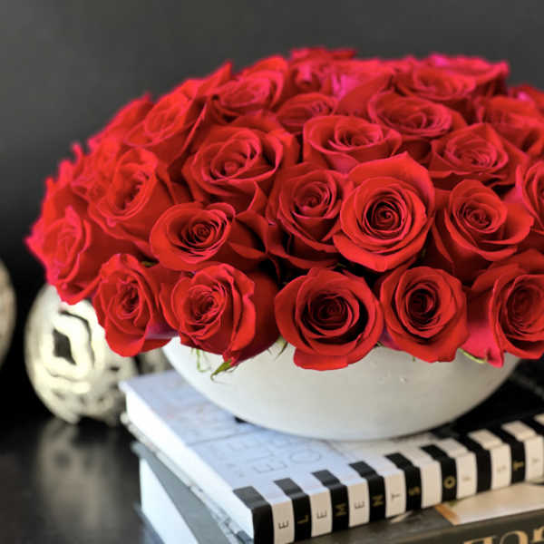 Round arrangement of red roses in a white bowl vase