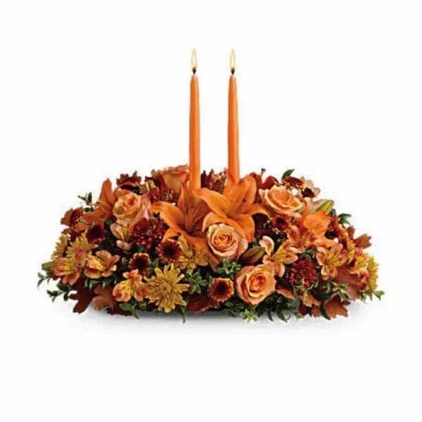 Orange floral centerpiece with two taper candles
