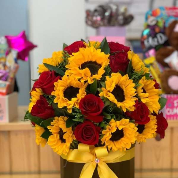 Bouquet of red roses and yellow sunflowers in a black box with a yellow ribbon