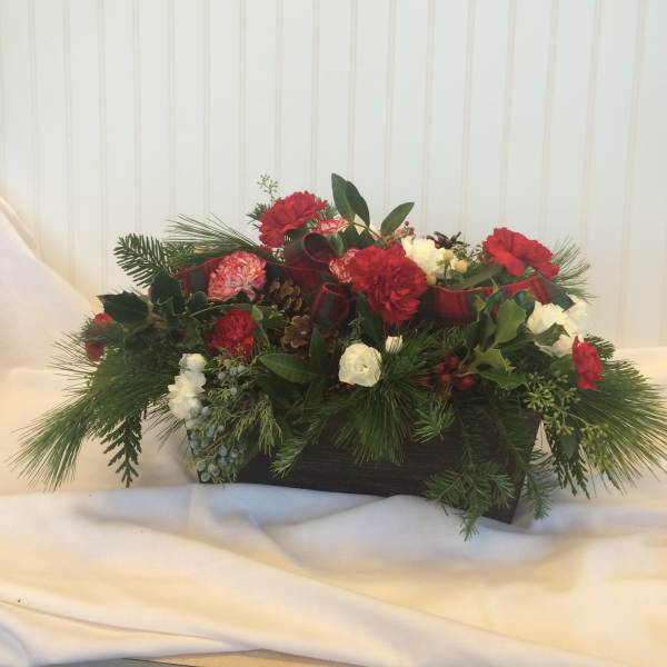 Holiday centerpiece with red and white carnations in a low rectangular container