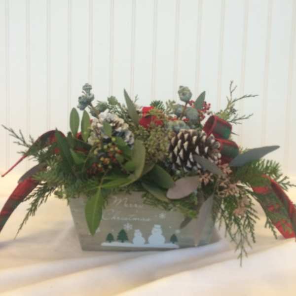 Holiday arrangement in a decorative box with pinecones and ribbon