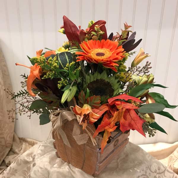 Autumn floral arrangement in a wooden box with orange gerbera daisies and lilies