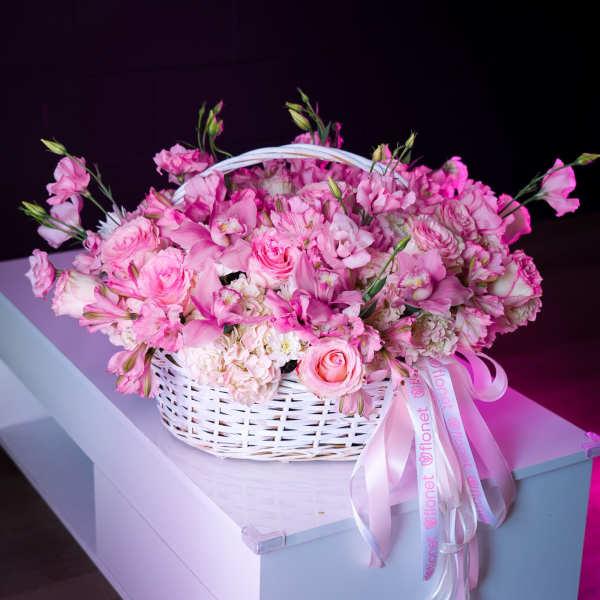 Pink flower basket with roses and orchids in a white wicker basket