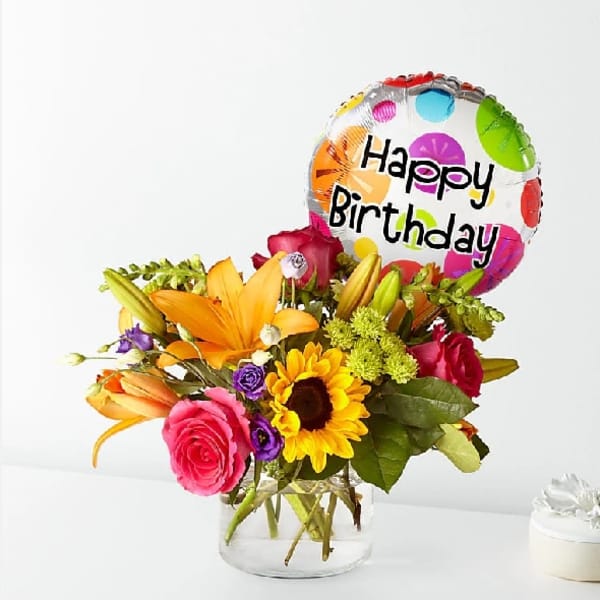 Mixed flower bouquet in a glass vase with a Happy Birthday balloon