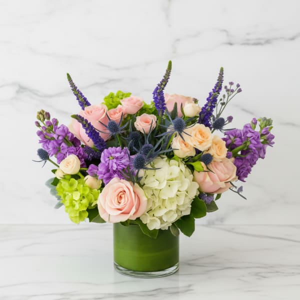 Bouquet of pink and cream roses with purple flowers in a green vase