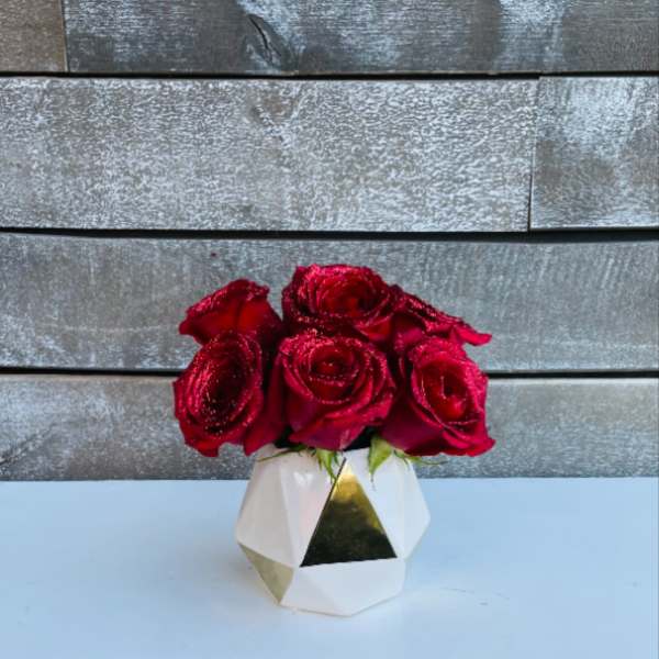 Red roses in a geometric white vase with gold accents