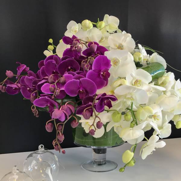 Purple and white orchid arrangement in a glass vase