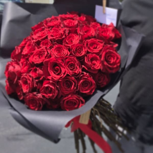 Bouquet of red roses wrapped in black paper with a red ribbon