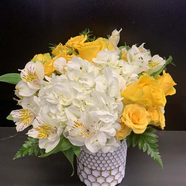 Yellow roses and white hydrangeas in a patterned vase