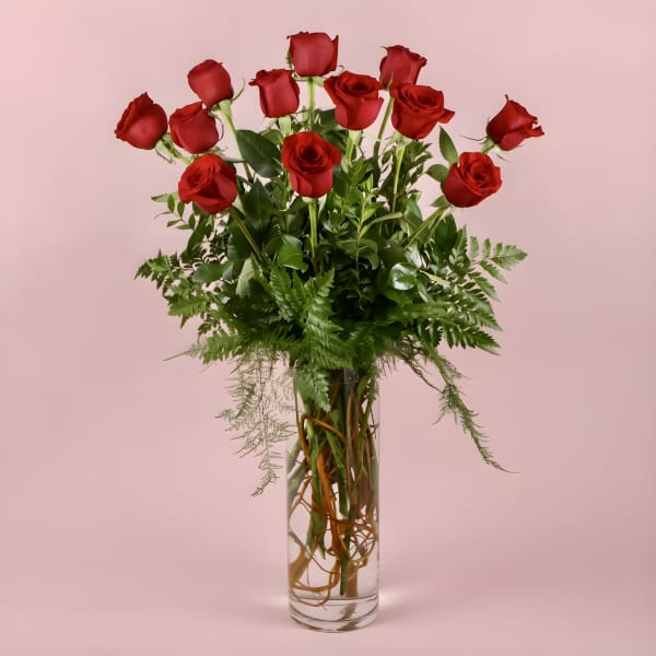 Red roses arranged in a tall clear glass vase