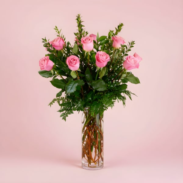 Pink roses arranged in a tall clear glass vase