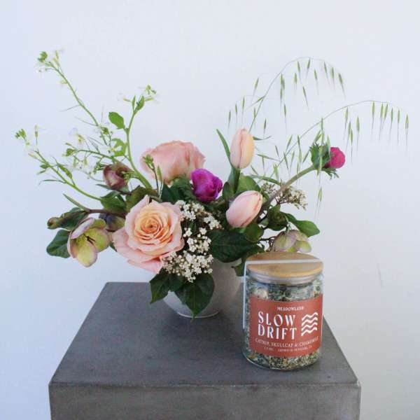 Pink rose bouquet in a vase beside a labeled glass jar candle