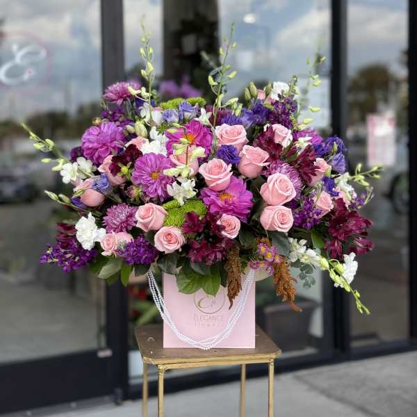 Large pink and purple floral arrangement in a pink gift bag