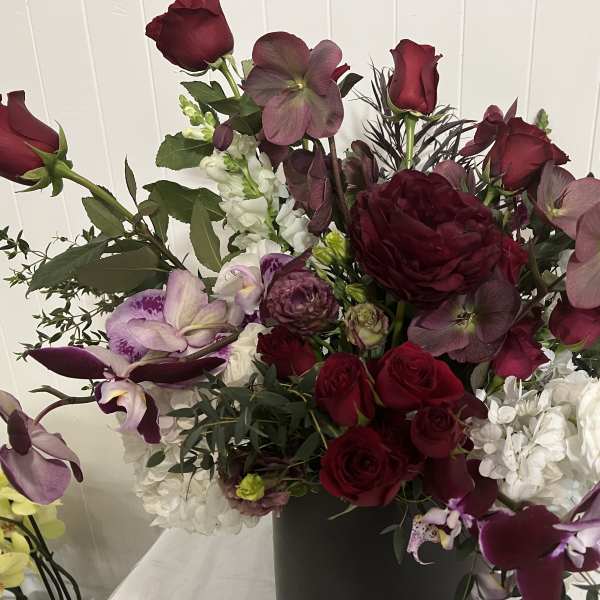 Deep burgundy and white floral arrangement in a black vase