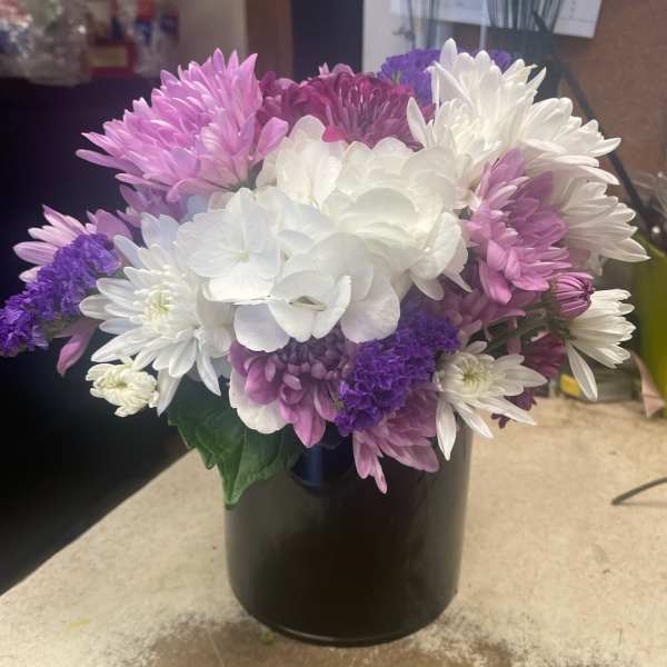Bouquet of white, pink, and purple chrysanthemums in a black vase