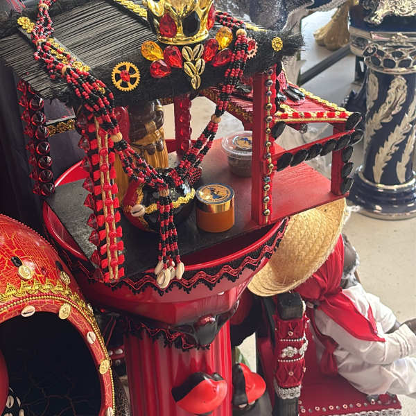 Decorative ceremonial display with red and black beaded adornments and a crown