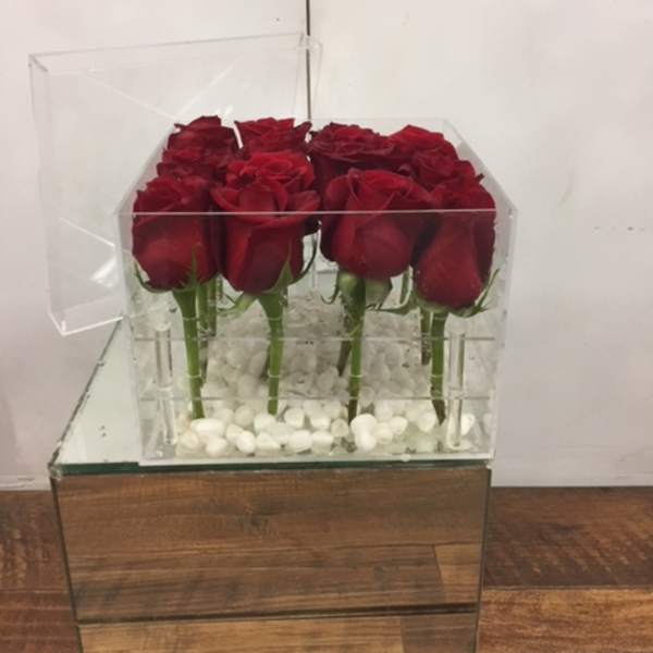 Red roses arranged in a clear acrylic box with white stones