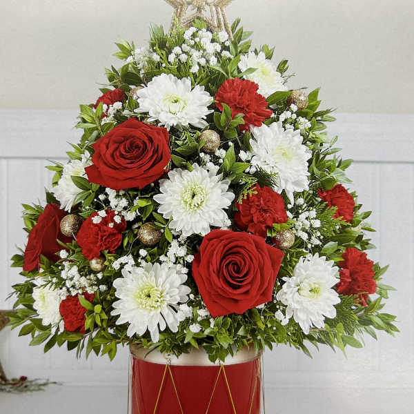 Red roses and white chrysanthemums arranged in a red drum container with a star topper