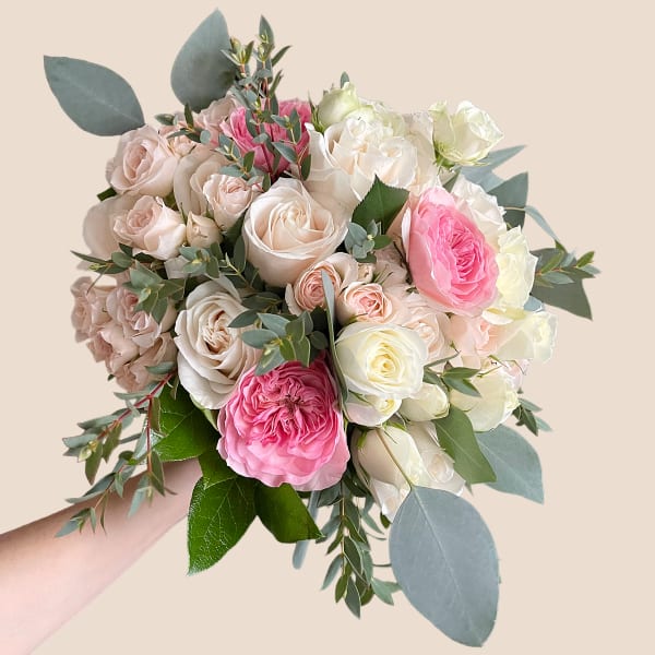 Handheld bouquet of pink and white roses with eucalyptus