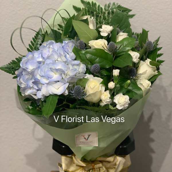 Bouquet of blue hydrangea and white roses wrapped in green paper