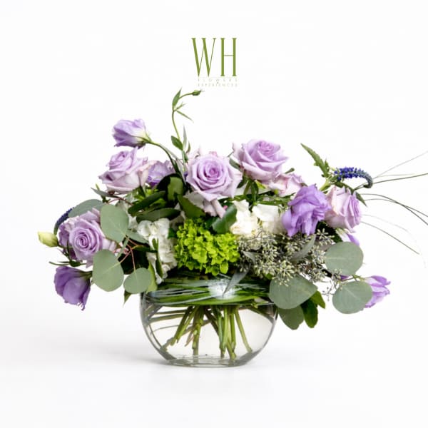 Lavender roses and white flowers in a clear glass bowl vase