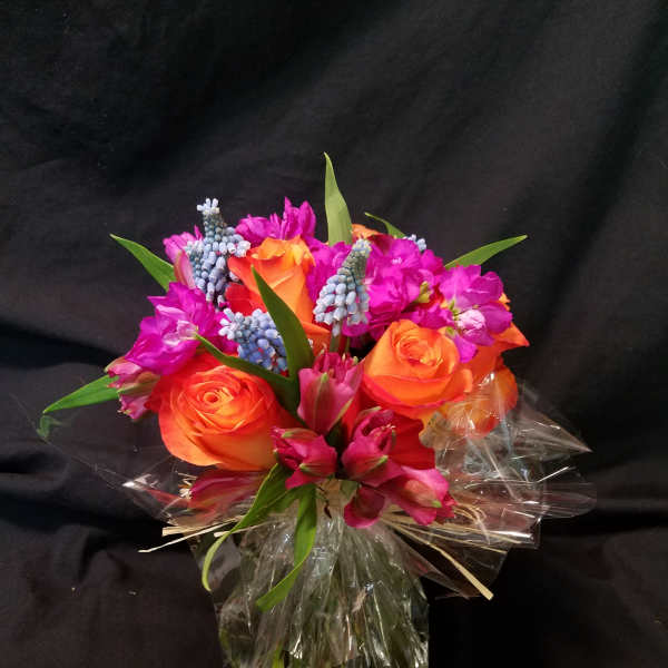Bouquet of orange roses and magenta flowers wrapped in clear plastic