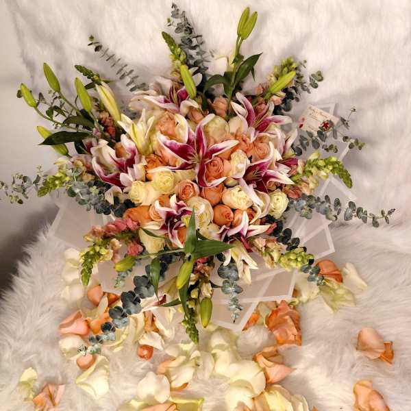 Bouquet of peach roses and white lilies with eucalyptus accents