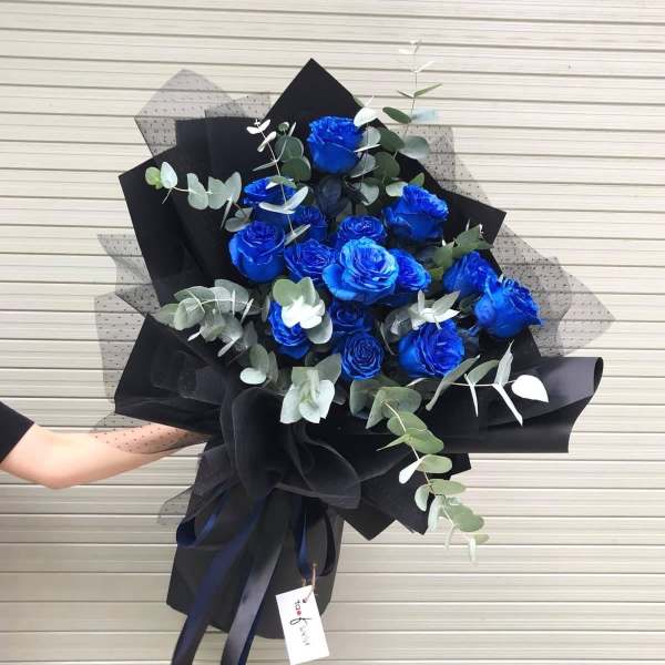 Bouquet of vivid blue roses with eucalyptus in black wrapping