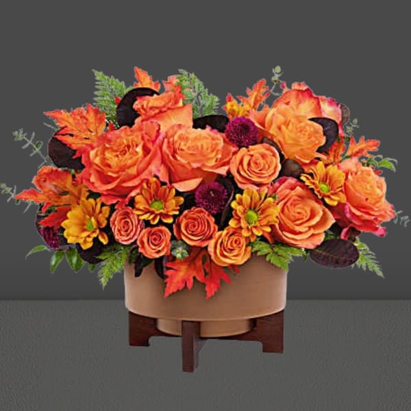 Orange roses and autumn flowers in a round container