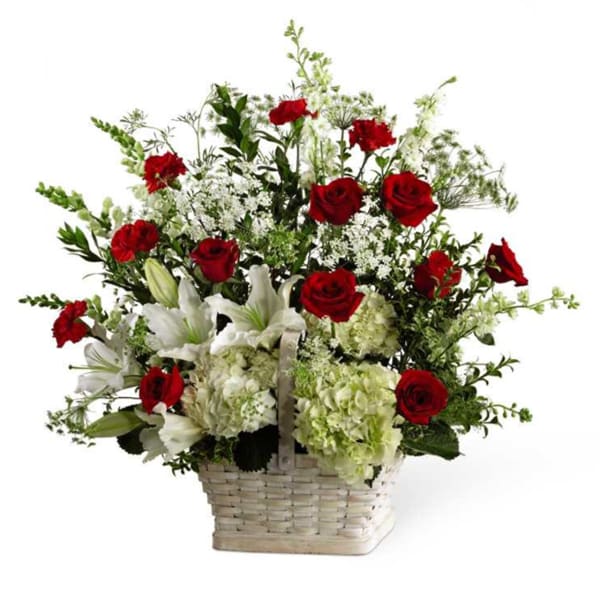 Tall basket arrangement of red roses, white lilies, and green hydrangeas in a white woven basket