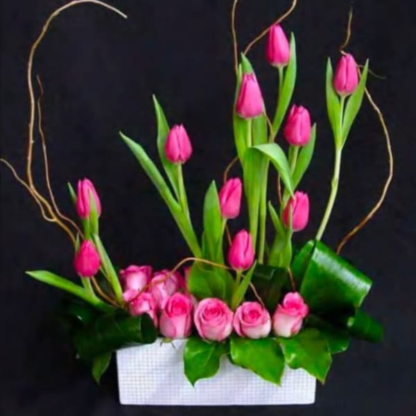 Pink tulips and roses arranged in a white rectangular container