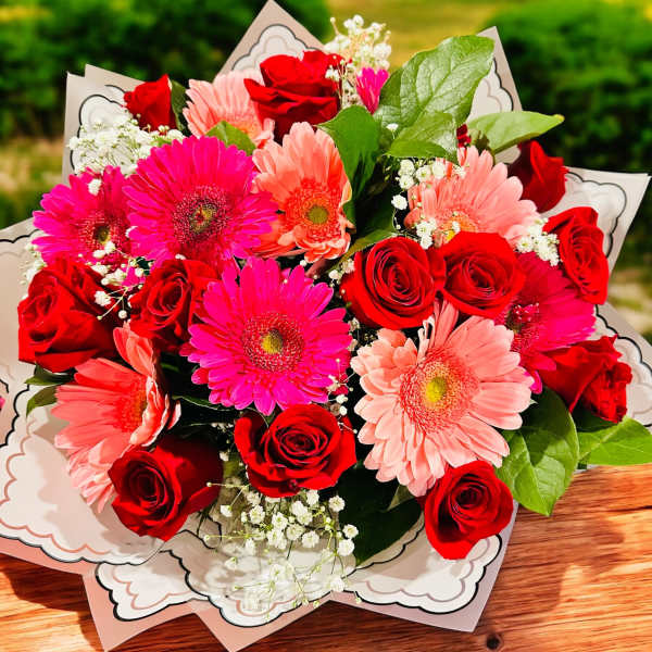 Bouquet of red roses and pink gerbera daisies in decorative wrap