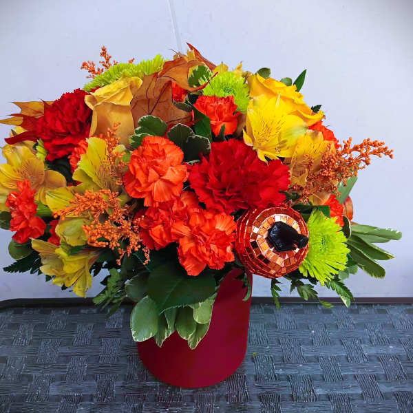 Bright autumn bouquet with red, orange, and yellow flowers in a red vase