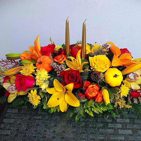 Bright floral centerpiece with roses, lilies, and candles