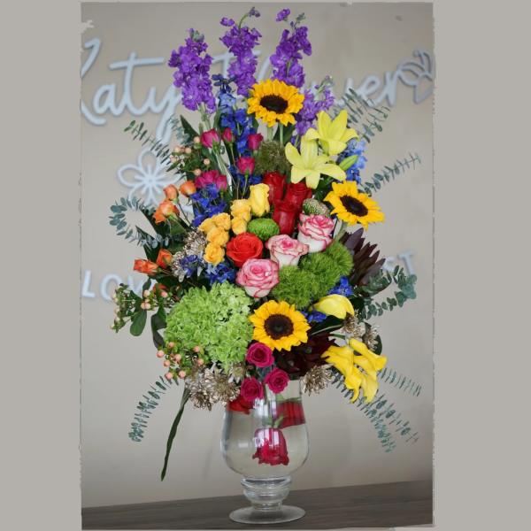 Tall mixed arrangement with sunflowers, roses, lilies, hydrangea and calla lilies in a clear glass vase