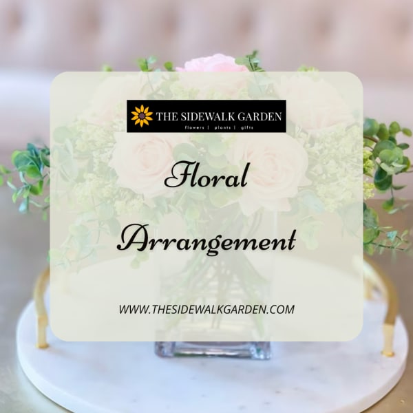 Blush roses in a clear square vase with greenery