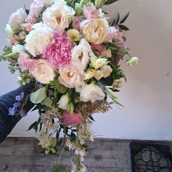 Handheld bouquet of pale pink and white flowers with trailing blooms