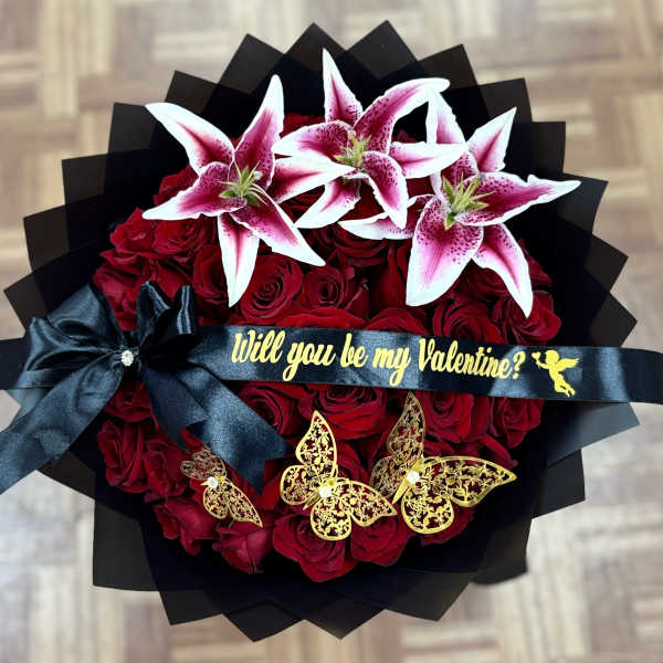 Bouquet of red roses topped with pink-and-white lilies and a black ribbon