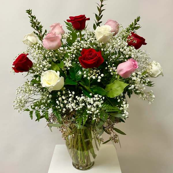 Bouquet of red, pink, and white roses in a clear glass vase