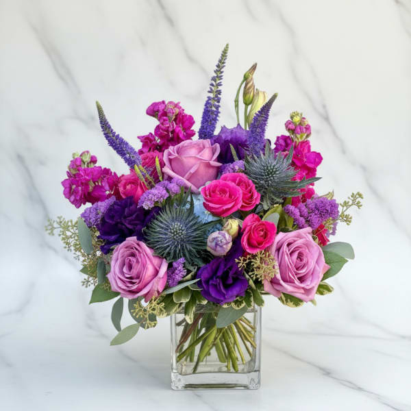Purple and pink rose bouquet in a clear glass vase