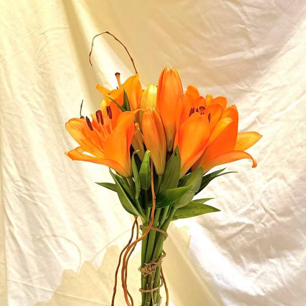 Orange lilies and pink roses arranged in a tall vase