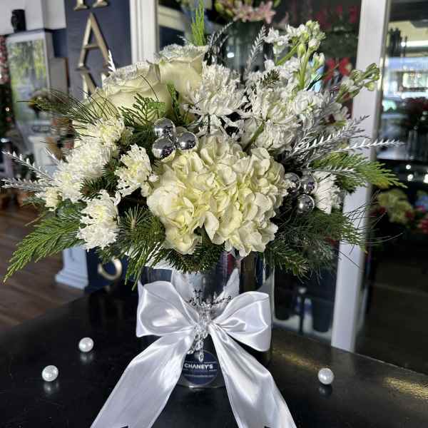 White floral arrangement in a silver vase with a satin bow
