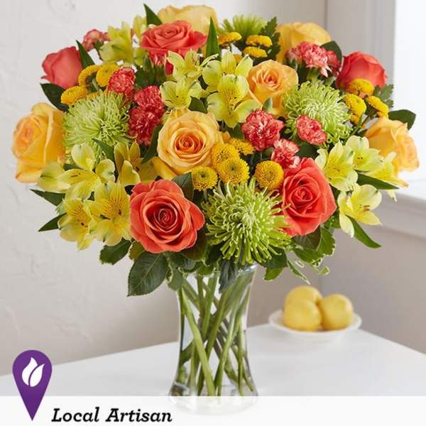 Mixed bouquet of roses, lilies, and mums in a glass vase
