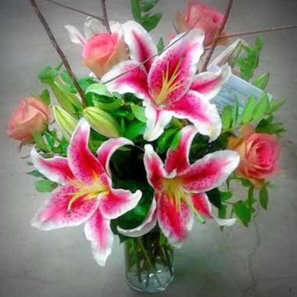 Bouquet of pink lilies and roses in a clear glass vase