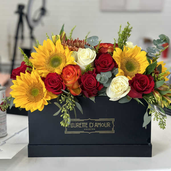 Sunflowers and roses arranged in a black box